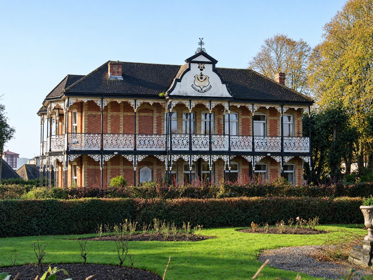 The front of Higher Park Lodge, its two tiers of ironwork verandahs looking out over the park gardens.