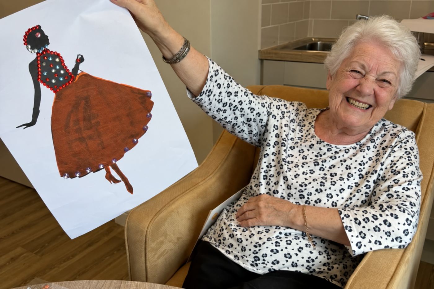 A smiling resident holding up a drawing she has made.